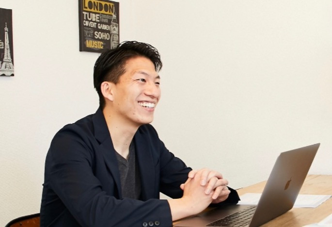 パソコンの前で話す秋山典男さん